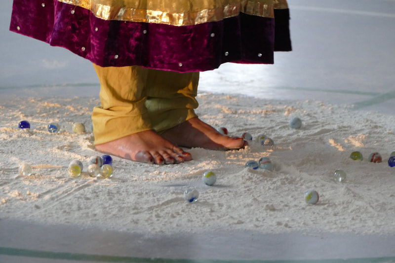 a woman's feet standing in a circle of flour surrounded by marbles